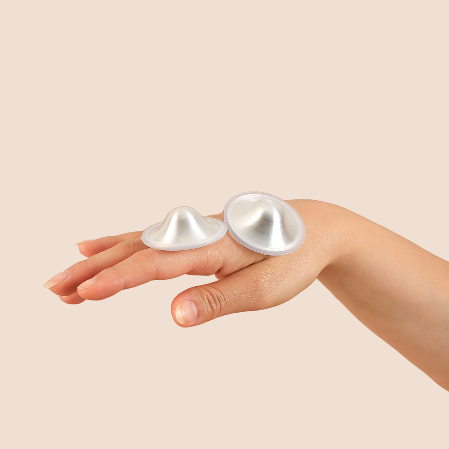 Silver nursing cups resting on a hand