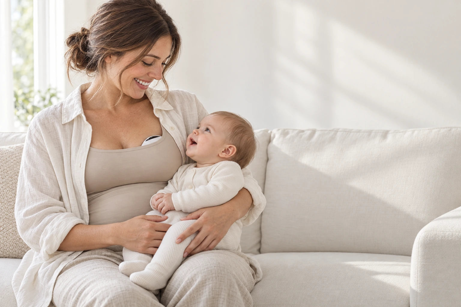A mum sharing a relaxed moment with her baby on the sofa, with Luna discreetly inside her nursing top