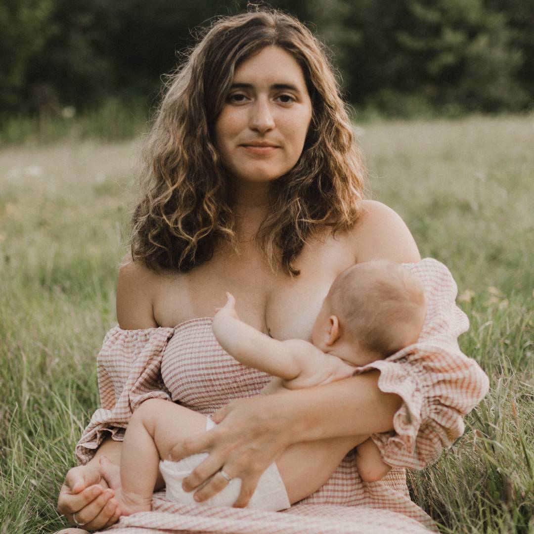 A mother breastfeeds her baby outdoors.