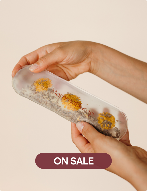 Hand holding a hot/cold perineal therapy gel pack with flowers inside and 'Mammapump' branding on a beige background.