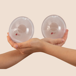 MammaBump breast milk collectors held in hands, designed to catch natural letdown while you nurse on the other side