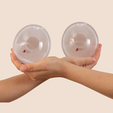 MammaBump breast milk collectors held in hands, designed to catch natural letdown while you nurse on the other side