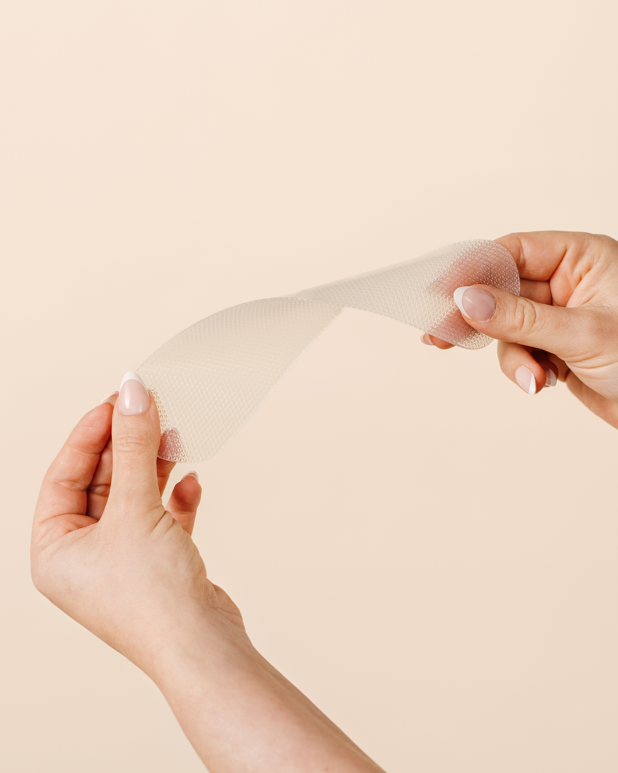 Close-up of hands demonstrating the flexibility of a MammaBump C-Section Silicone Scar Strip for gentle cesarean scar care