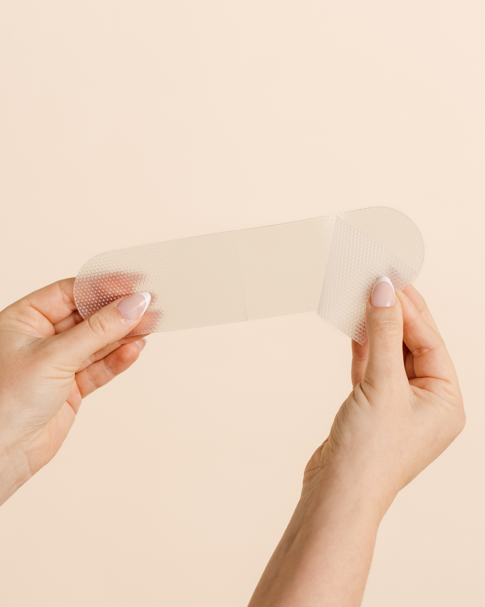 Close-up of hands demonstrating the soft, flexible texture of a MammaBump C-Section Silicone Scar Strip for scar care