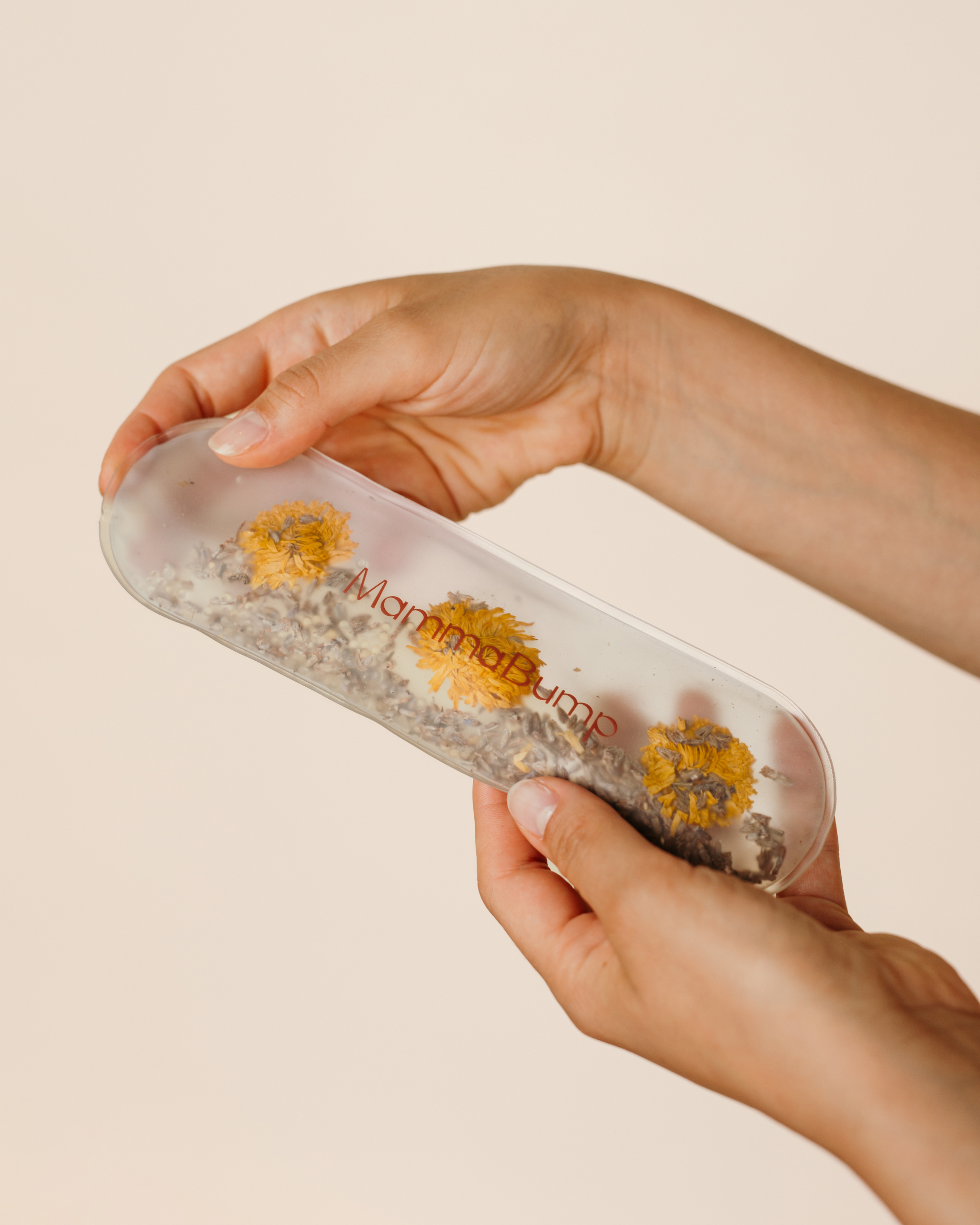 Close-up of hands demonstrating the MammaBump Perineal Hot & Cold Therapy Pack with chamomile and lavender inside for postpartum recovery