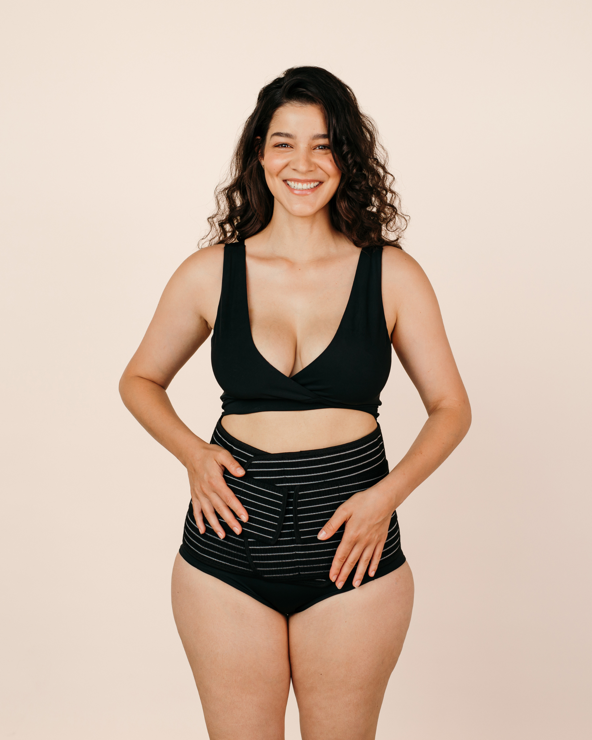 Smiling new mum confidently wearing the black MammaBump Postpartum Belly Band high-waisted for gentle support during postpartum recovery