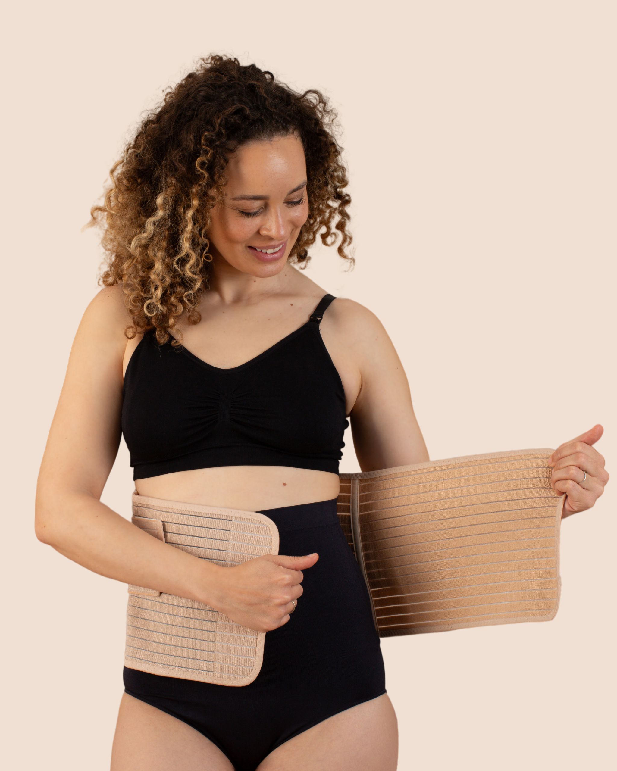 New mum wrapping the tan MammaBump Postpartum Belly Band around her midsection for gentle C-section recovery support