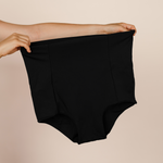 Hands holding up the black MammaBump Postpartum Soothing Brief, high-waisted and seamless for postpartum recovery