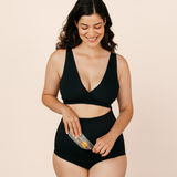 Smiling new mum placing the MammaBump Perineal Hot & Cold Therapy Pack into her black Postpartum Soothing Brief for soothing perineal relief