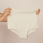 Hands holding up the cream MammaBump Postpartum Soothing Brief, high-waisted and seamless for postpartum recovery